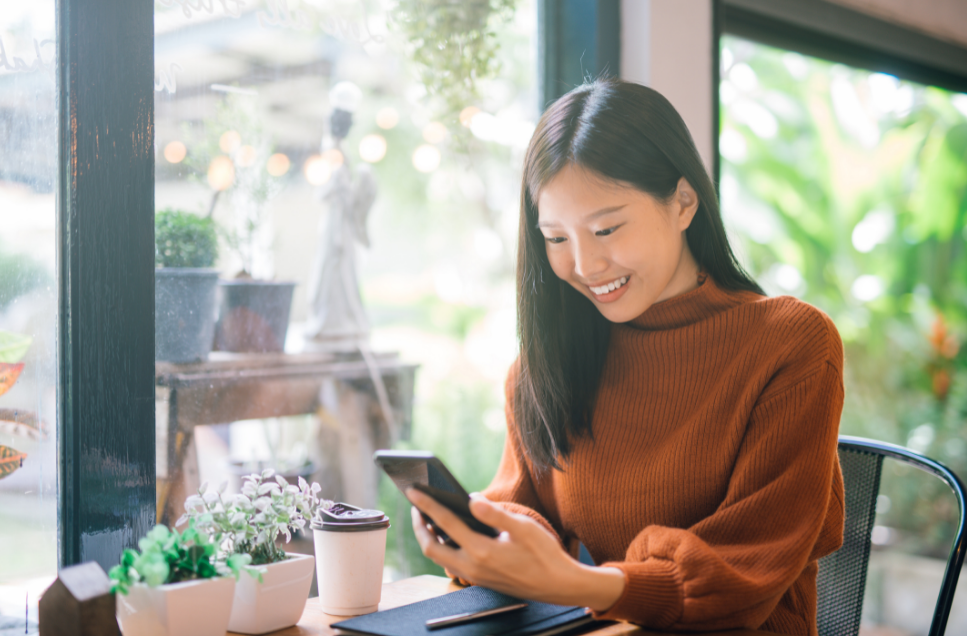 Woman smiling at phone while at coffee shop