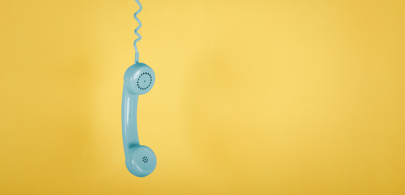 Teal phone hanging from cord on yellow background - Call Tracking