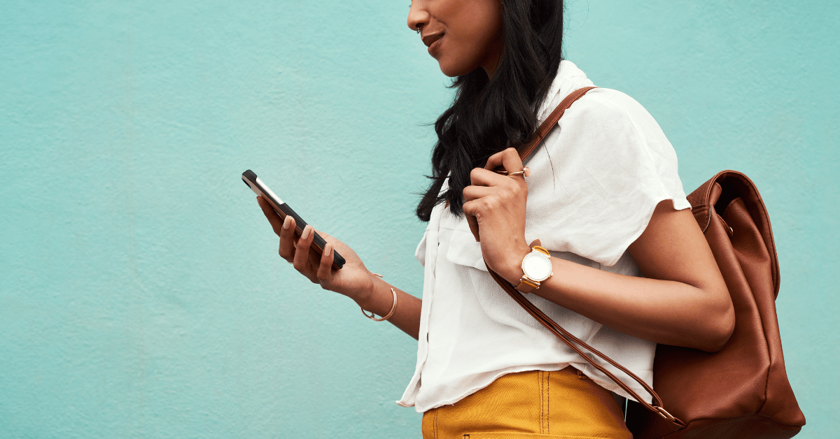 Cropped shot of an unrecognizable woman standing alone against a blue background and texting while in the city | Social Media for Small Businesses